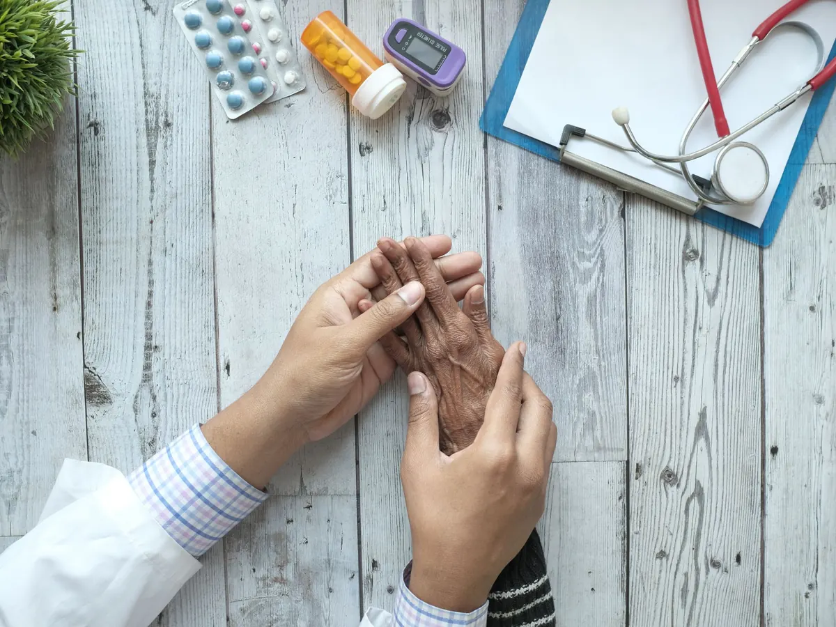 Médico tomando las manos de un paciente durante la consulta